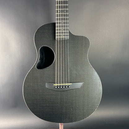 Carbon fiber acoustic guitar on a stand with a gray background