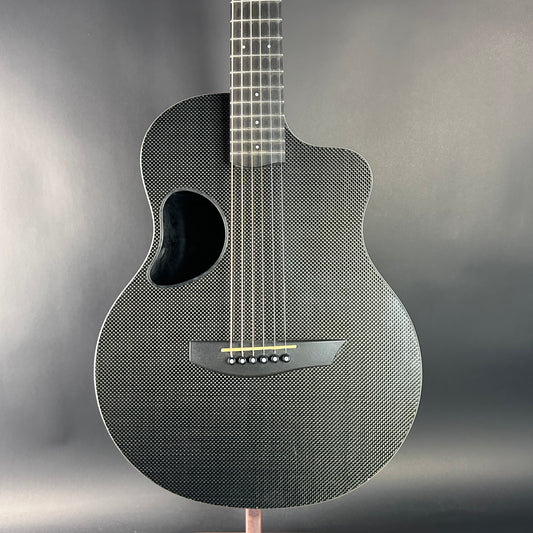 Carbon fiber acoustic guitar on a stand with a gray background