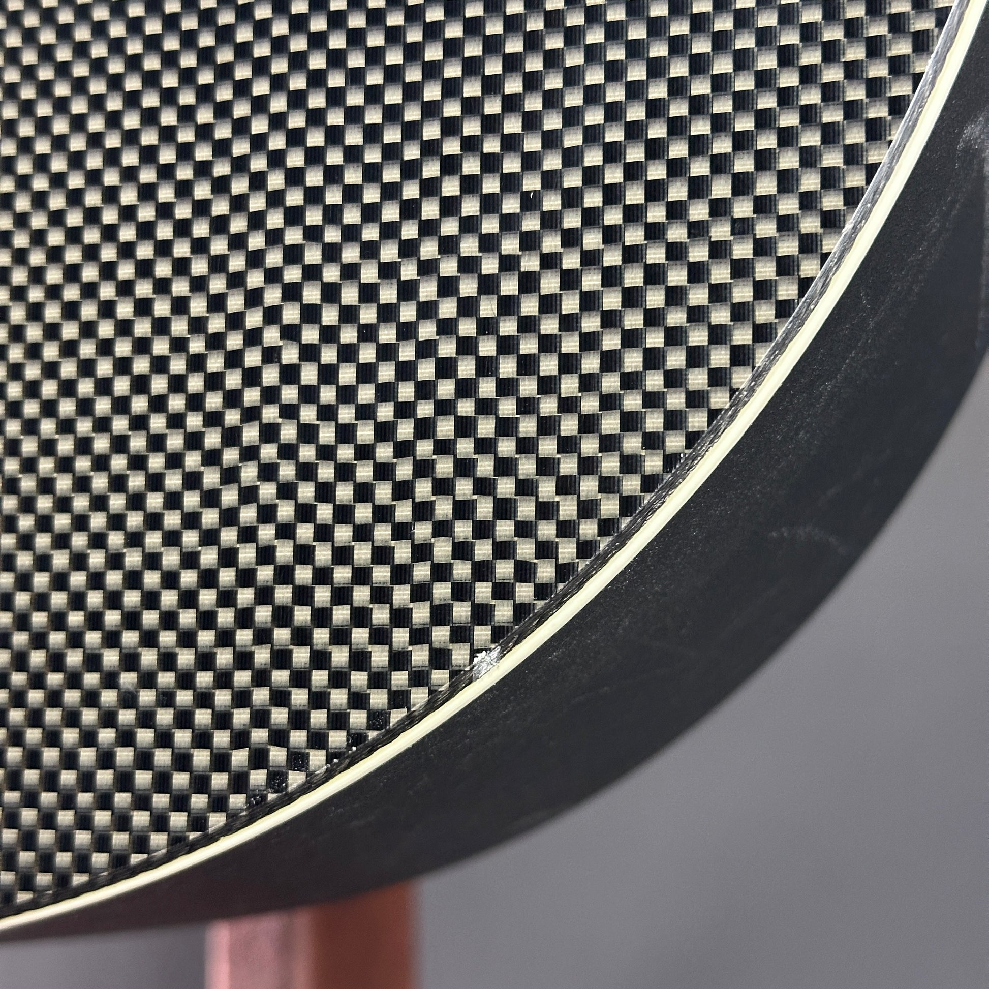 Close-up of a carbon fiber texture on a circular object with a blurred background