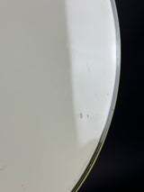 A close-up of a white circular product, likely a plate, tray, or shallow dish, showing a glossy white surface with a thin dark rim against a black background.