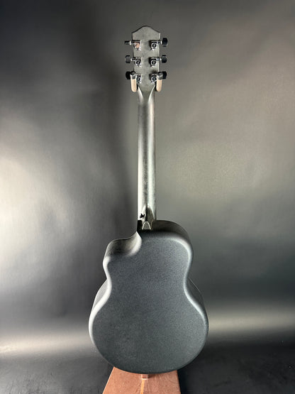 Close-up of a guitar's headstock and tuning pegs on a reflective surface.