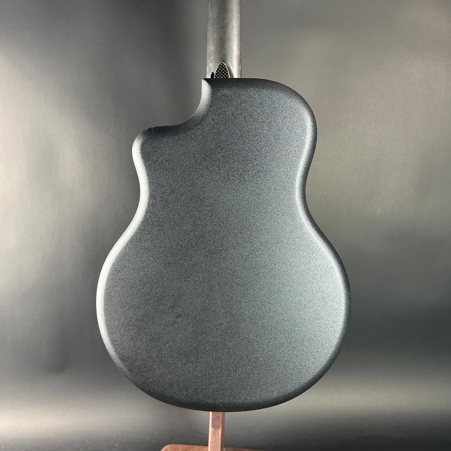Close-up of a textured guitar body on a stand with a neutral background