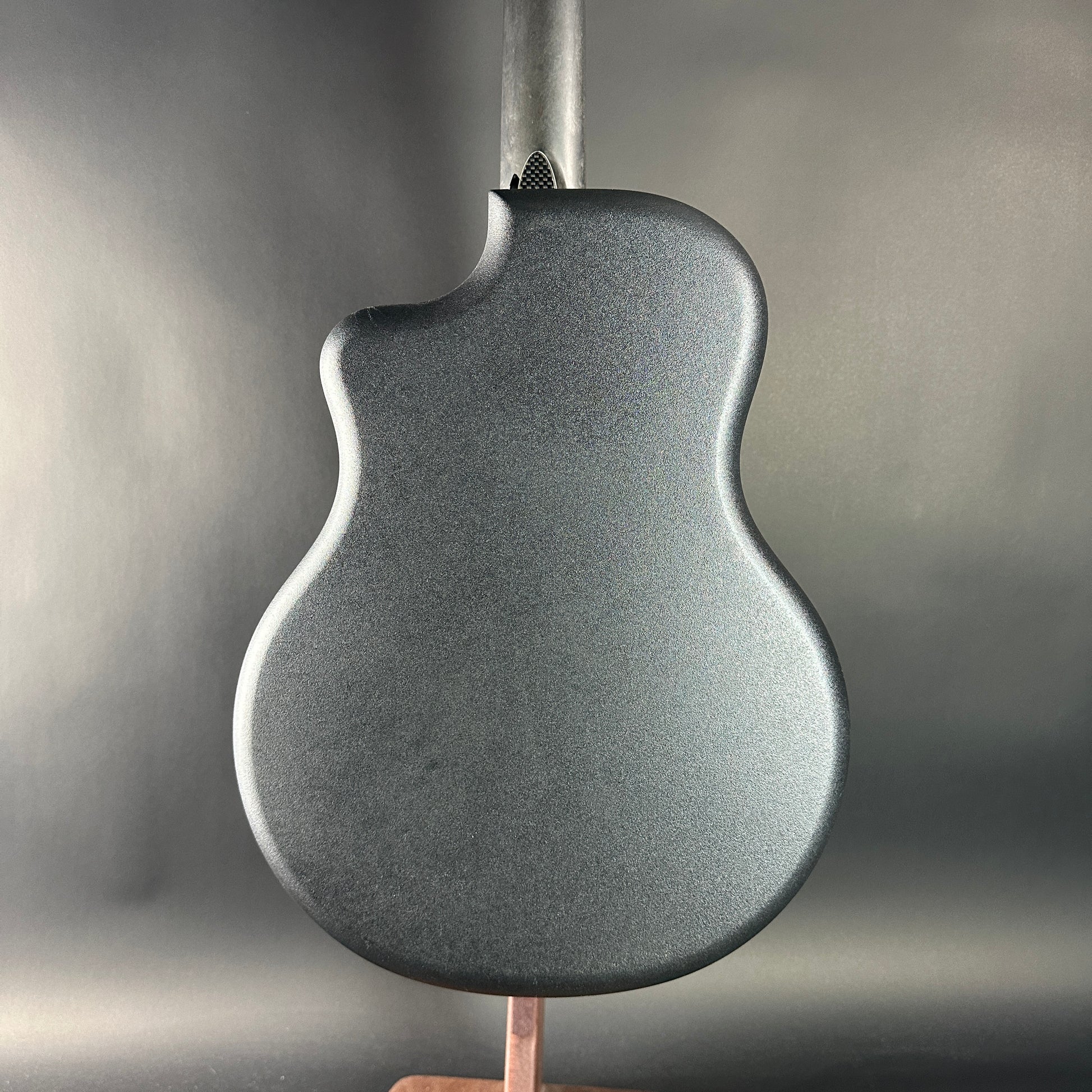 Close-up of a textured guitar body on a stand with a neutral background