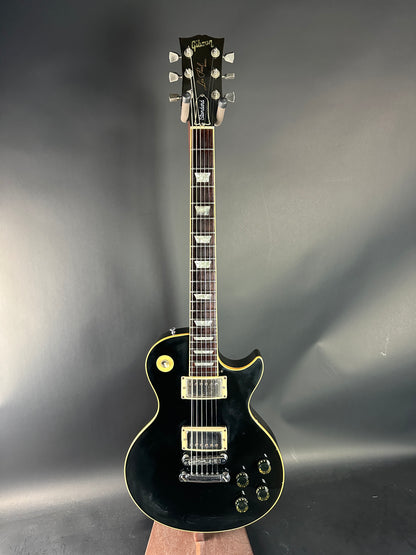 Black electric guitar on a reflective gray surface