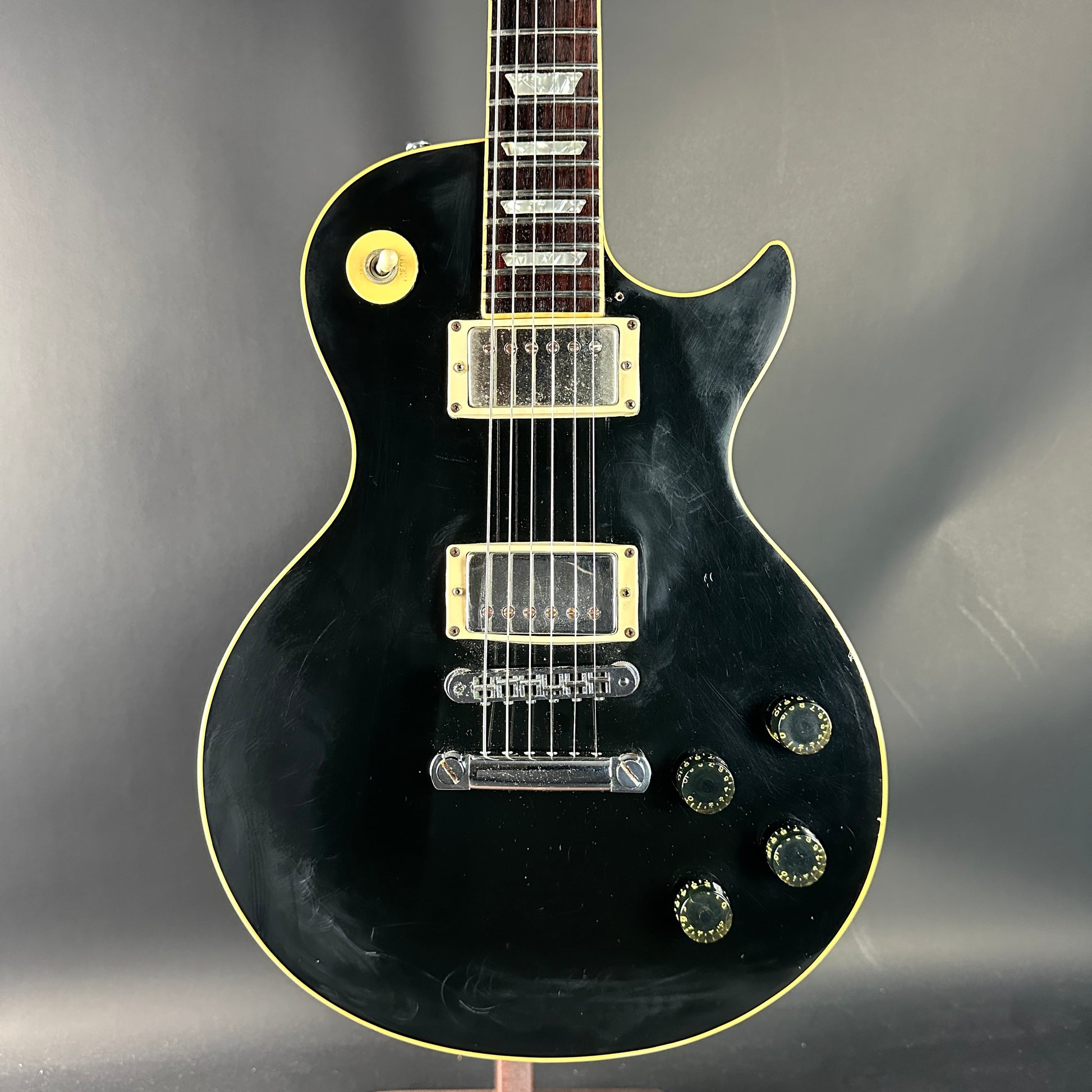Black electric guitar with gold hardware on a gray background