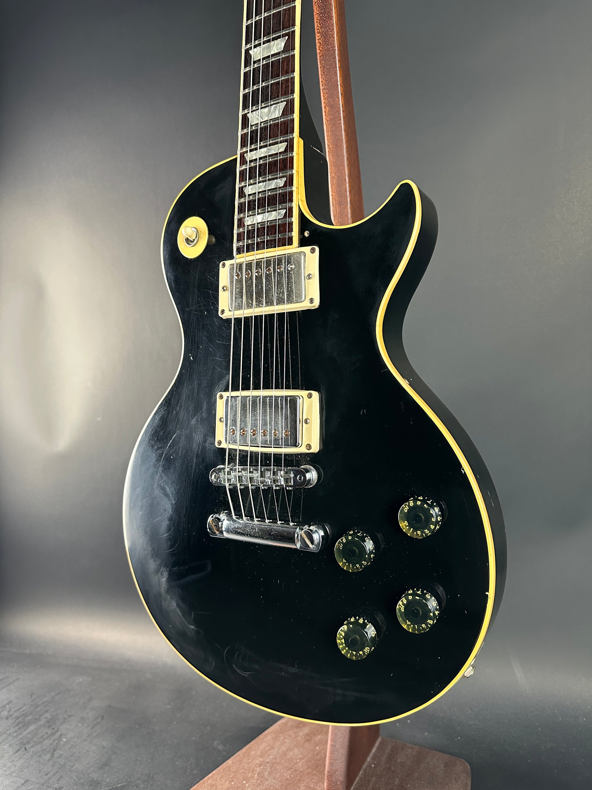 Black electric guitar with gold hardware on a gray background