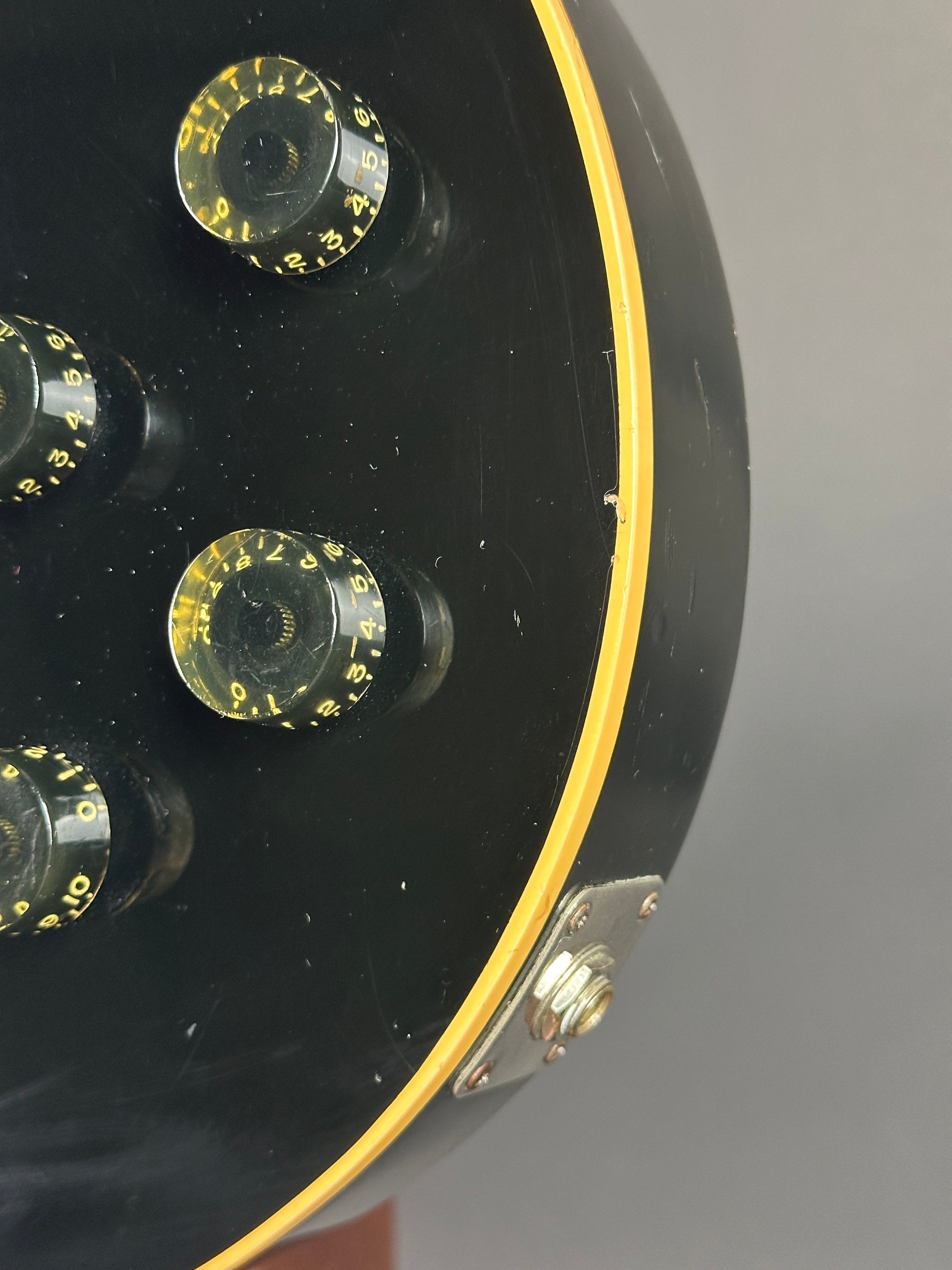 Close-up of a guitar headstock with tuning pegs on a gray background