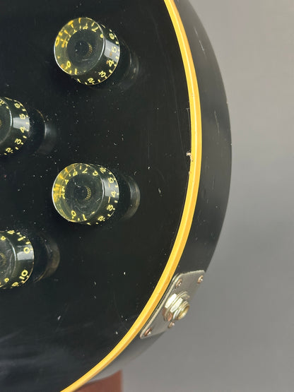 Close-up of a guitar headstock with tuning pegs on a gray background