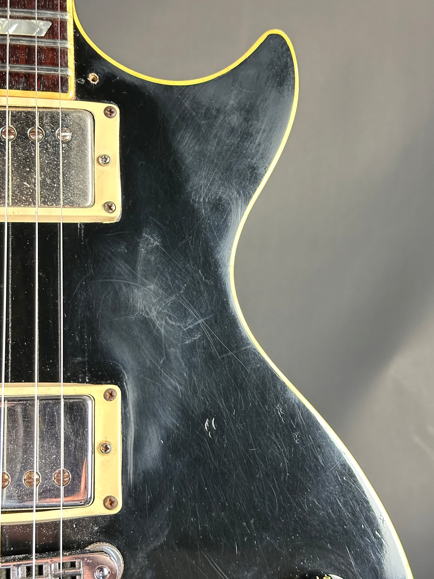 Close-up of a black electric guitar with visible wear on the body.