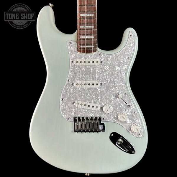 Electric guitar with a glittery body on a black background, featuring the Tone Shop logo.