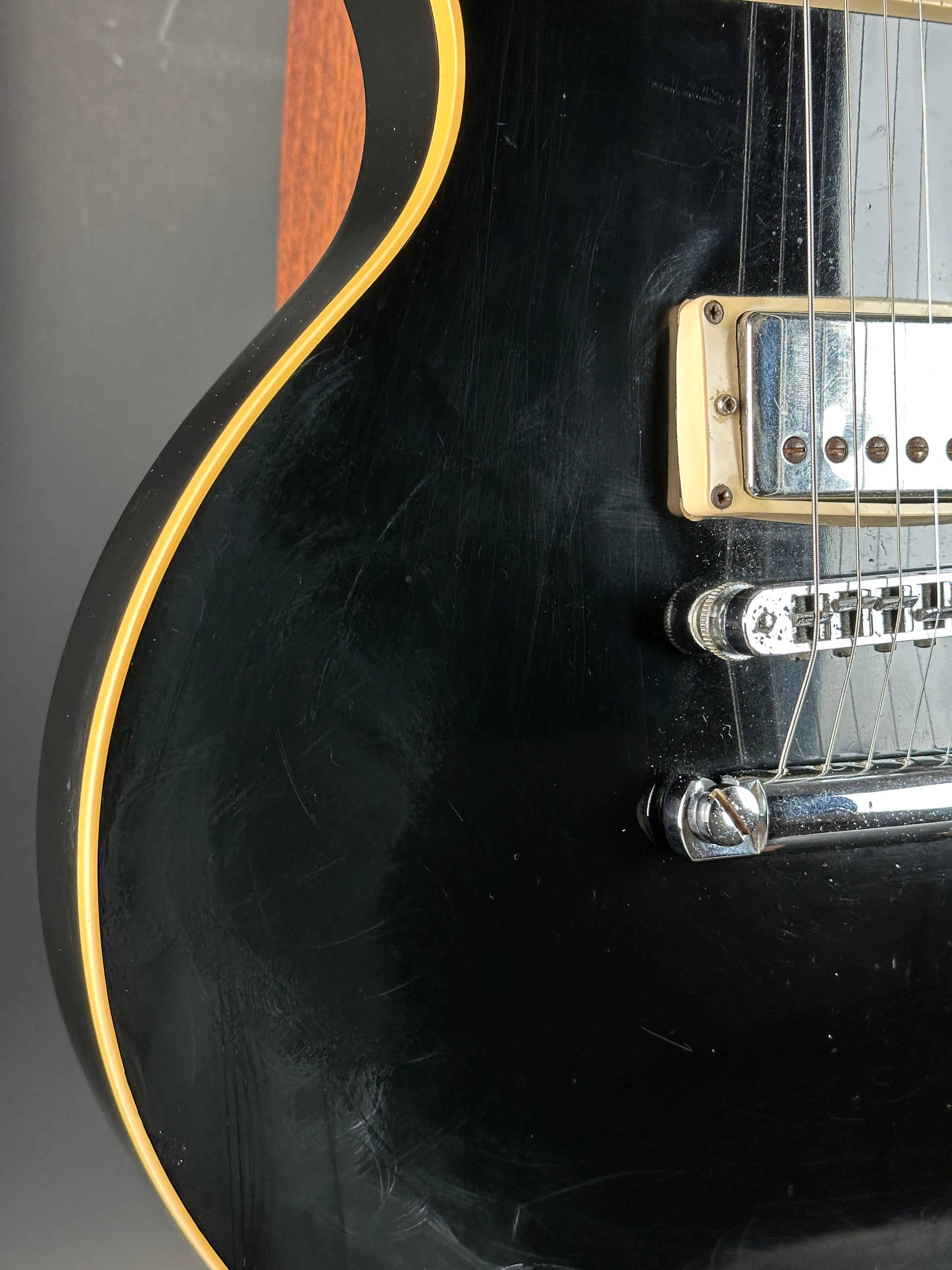 Close-up of a black electric guitar with visible wear on the body.