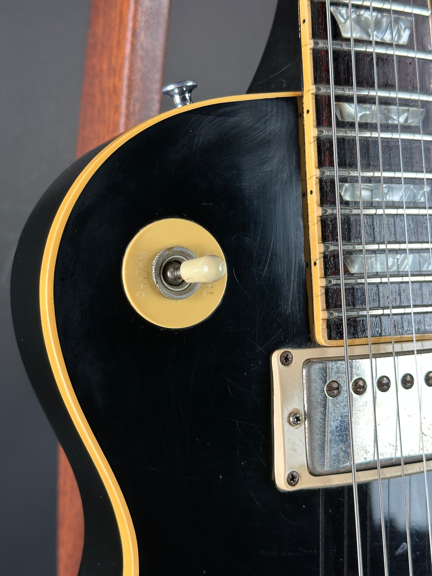 Close-up of a black electric guitar with a gold control knob on a dark background