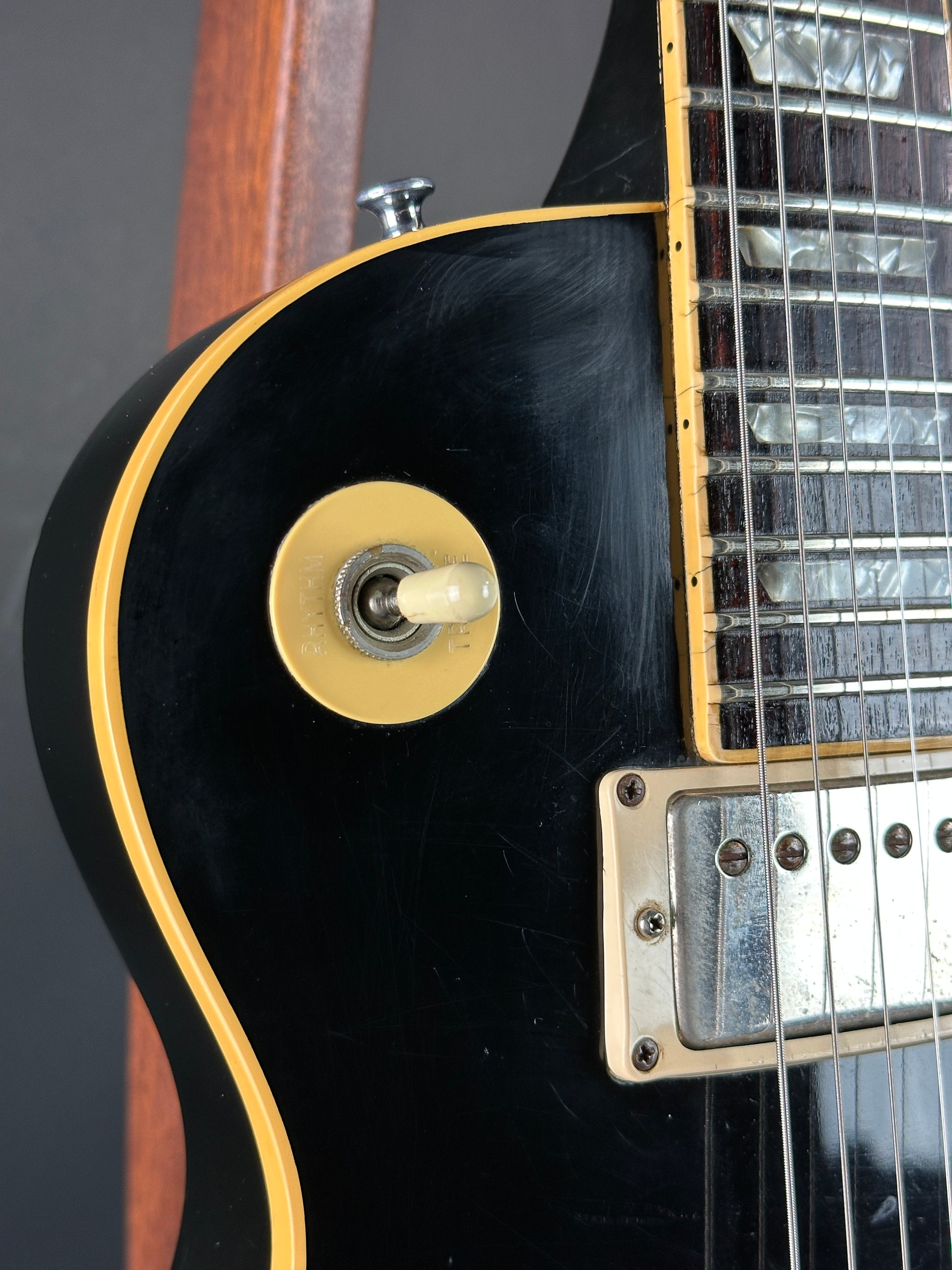 Close-up of a black electric guitar with a gold control knob on a dark background