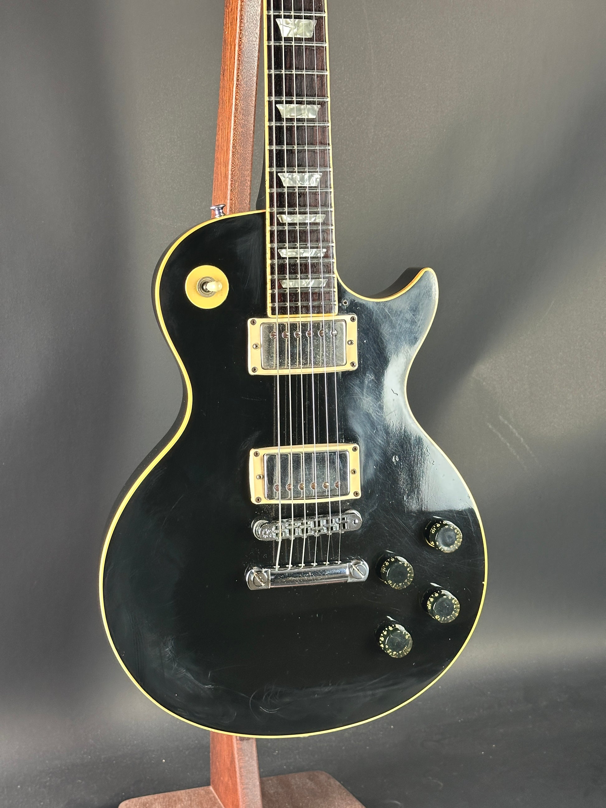 Black electric guitar with gold hardware on a dark background