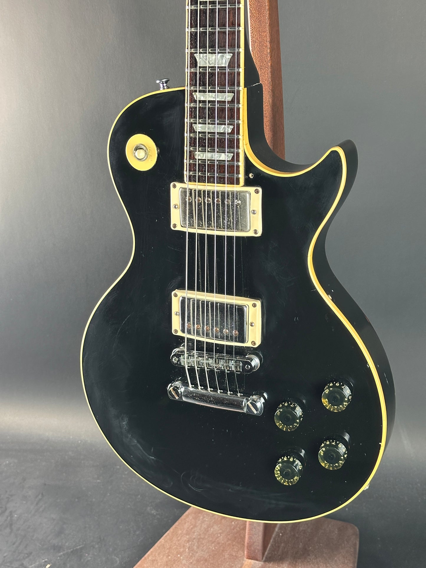 Black electric guitar with gold hardware on a gray background