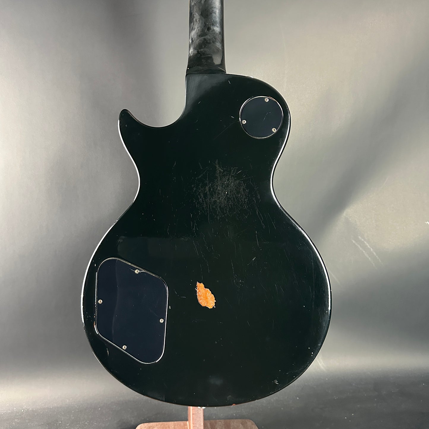 Black electric guitar on a stand against a gray background