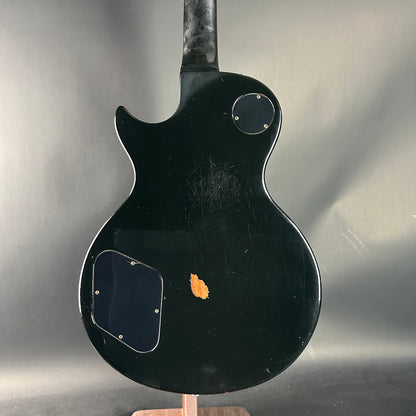 Black electric guitar on a stand against a gray background