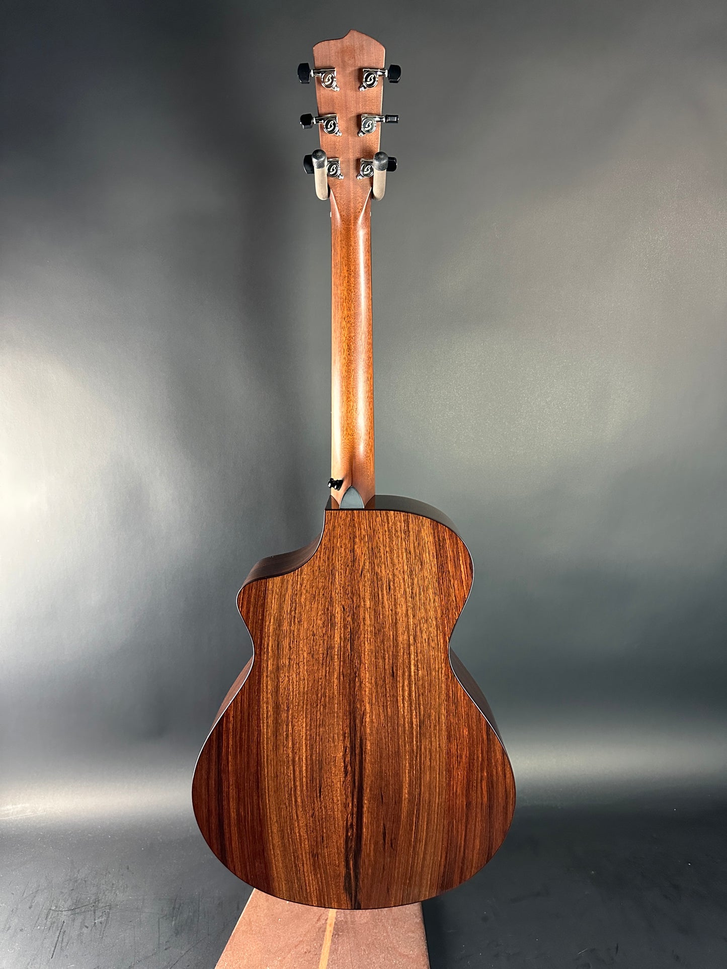 Wooden acoustic guitar on a reflective gray surface