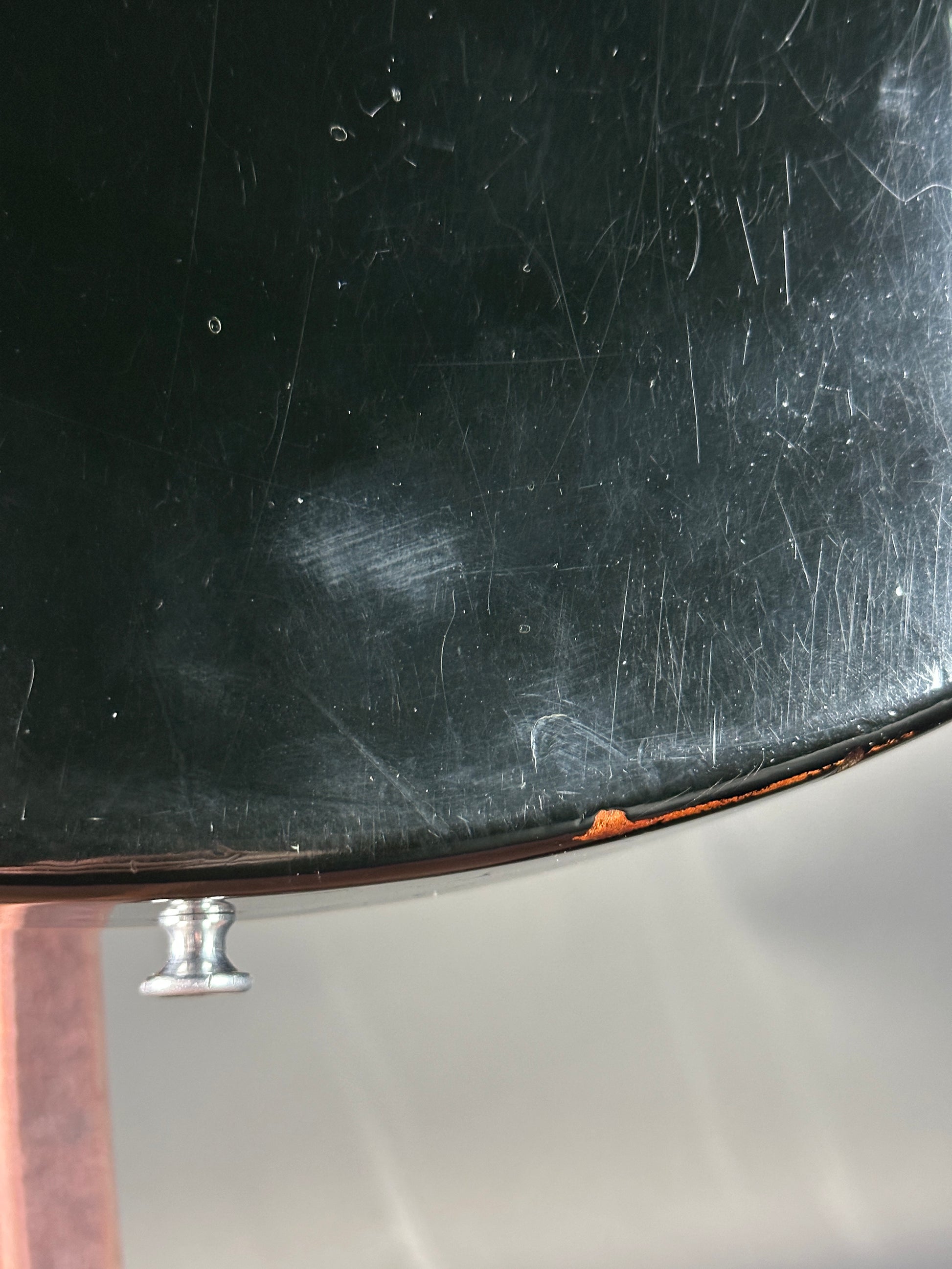 Scratched black surface with a metallic knob on a reflective background