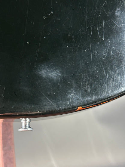 Scratched black surface with a metallic knob on a reflective background