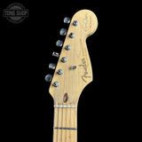 Close-up of a Fender Stratocaster electric guitar headstock in natural wood, featuring six silver tuning pegs and a black Fender logo, set against a solid black background.