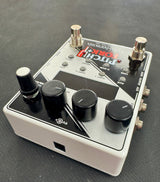 Guitar effects pedal with control knobs on a dark surface