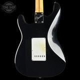 The back of a Fender electric guitar with a glossy black finish, a white pickguard, and a maple neck, shown against a black background with a Tone Shop watermark in the top left corner.