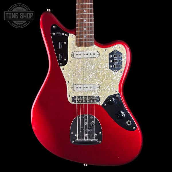 A red electric guitar with a cream pearlescent pickguard and black control plates, shown against a black background with a Tone Shop watermark in the top left corner.