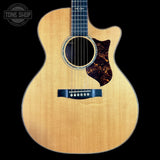 Acoustic guitar with a cutaway on a black background, featuring the Tone Shop logo.