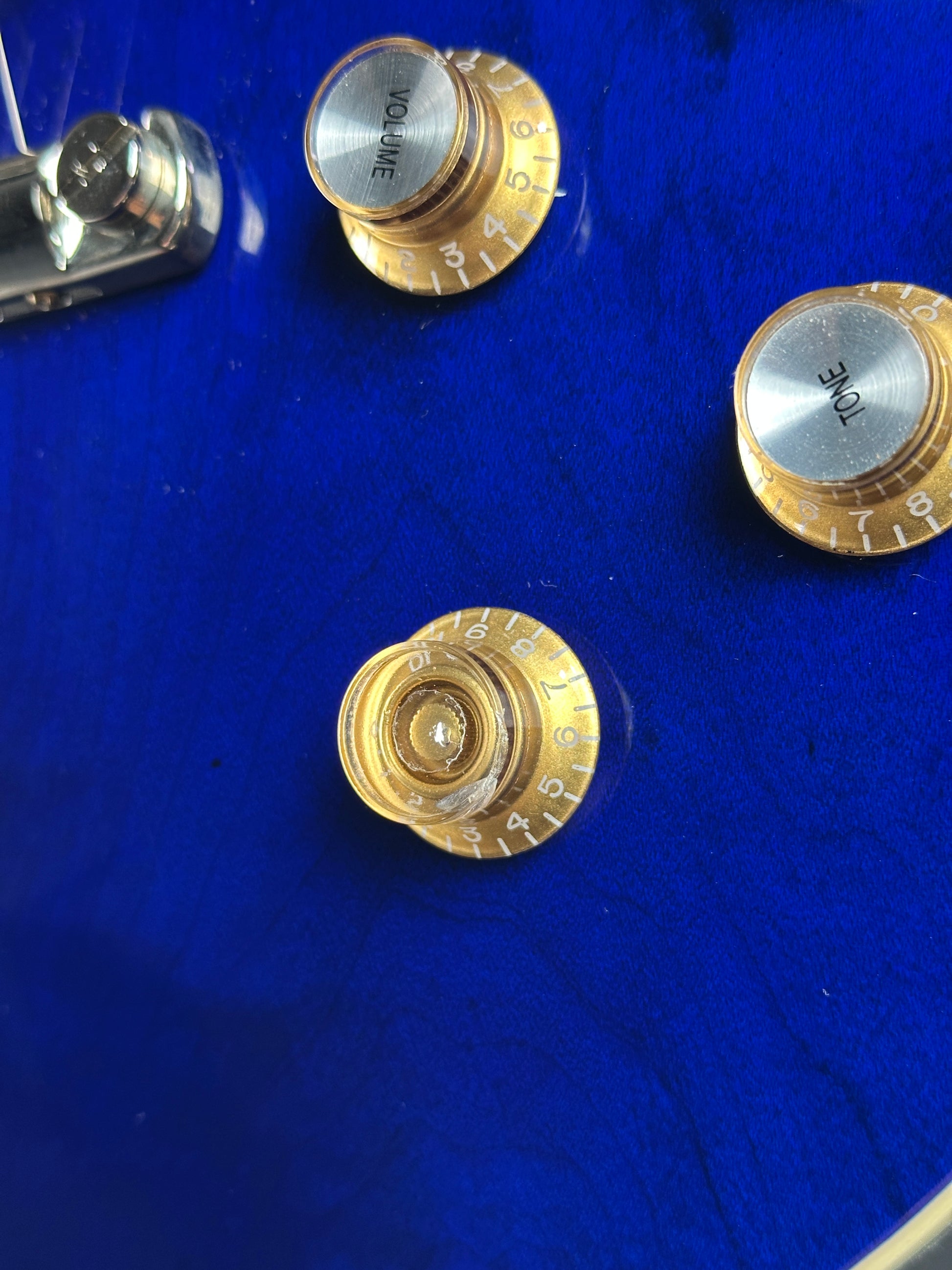 Close-up of guitar control knobs on a blue background