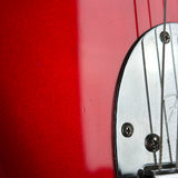 Close-up detail of a red electric guitar body with a chrome hardware component and strings.