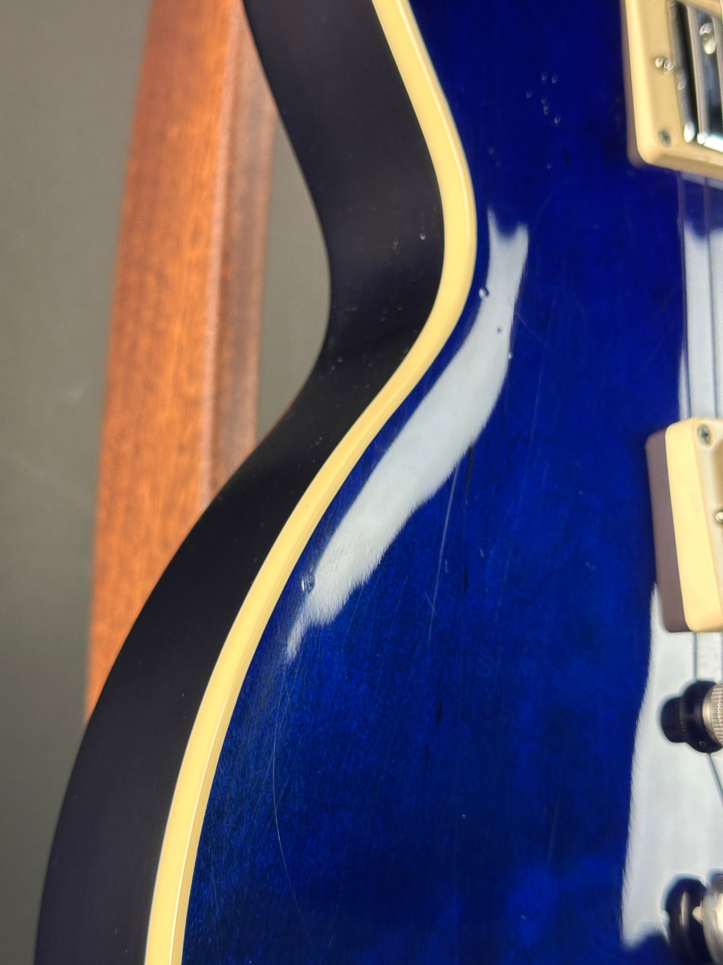 Close-up of a blue guitar with a visible scratch on the body