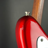 Close-up of a glossy red electric guitar body with a white pickguard and part of a wooden neck against a dark gray background.