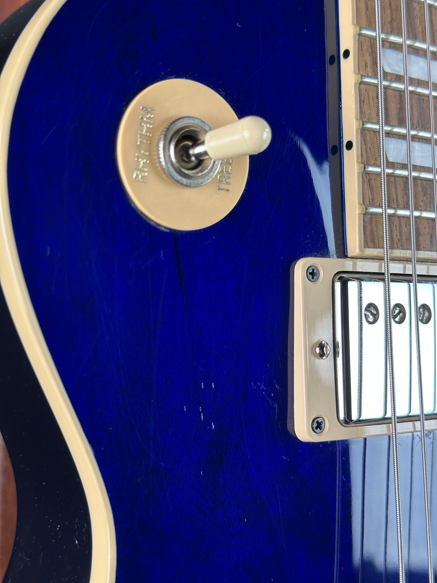 Close-up of a blue electric guitar with a control knob