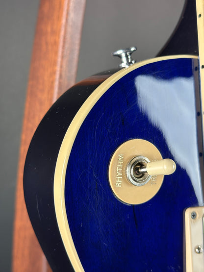 Close-up of a blue electric guitar with a gold switch plate.