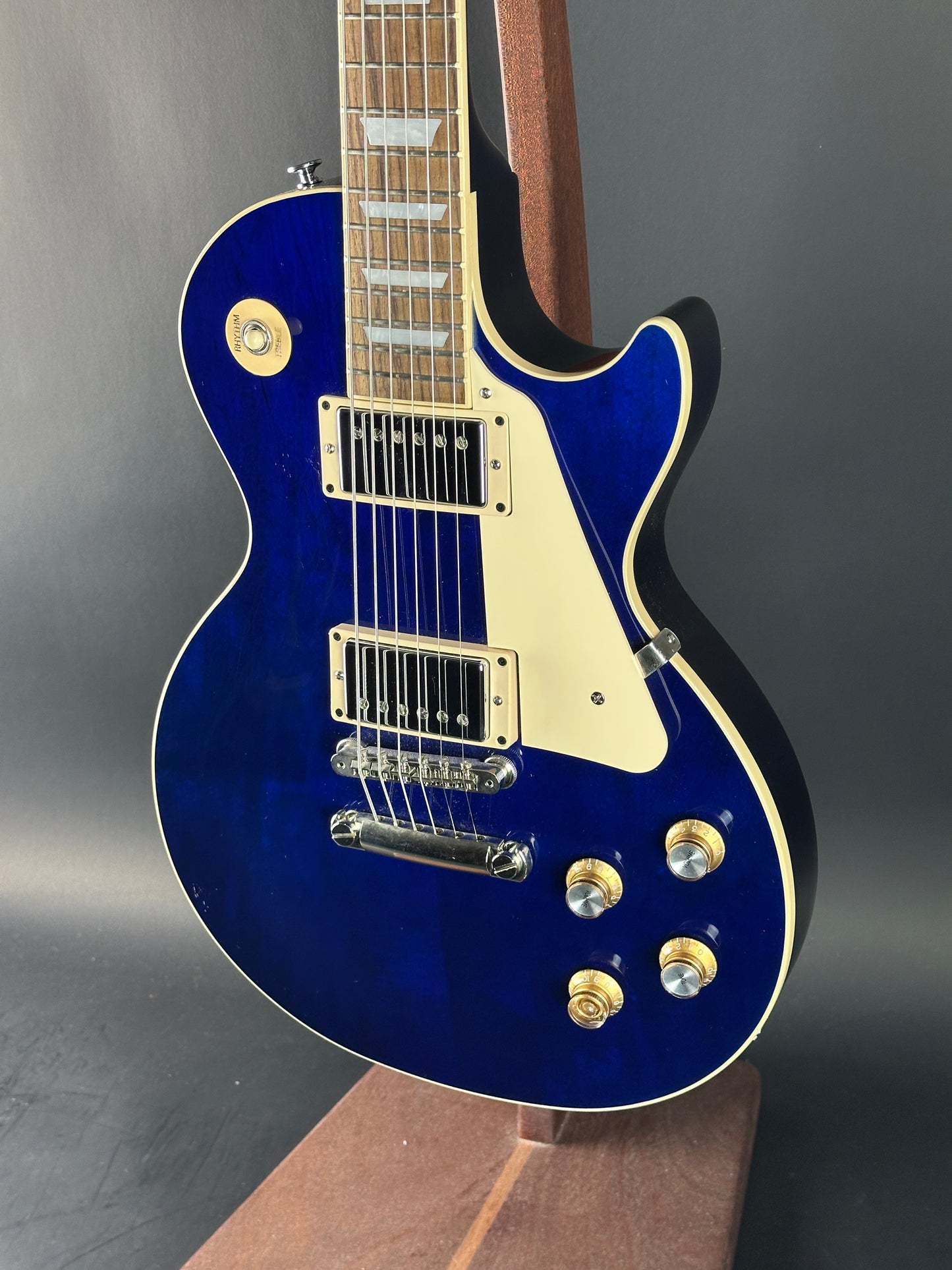 Blue electric guitar with a white pickguard on a gray background