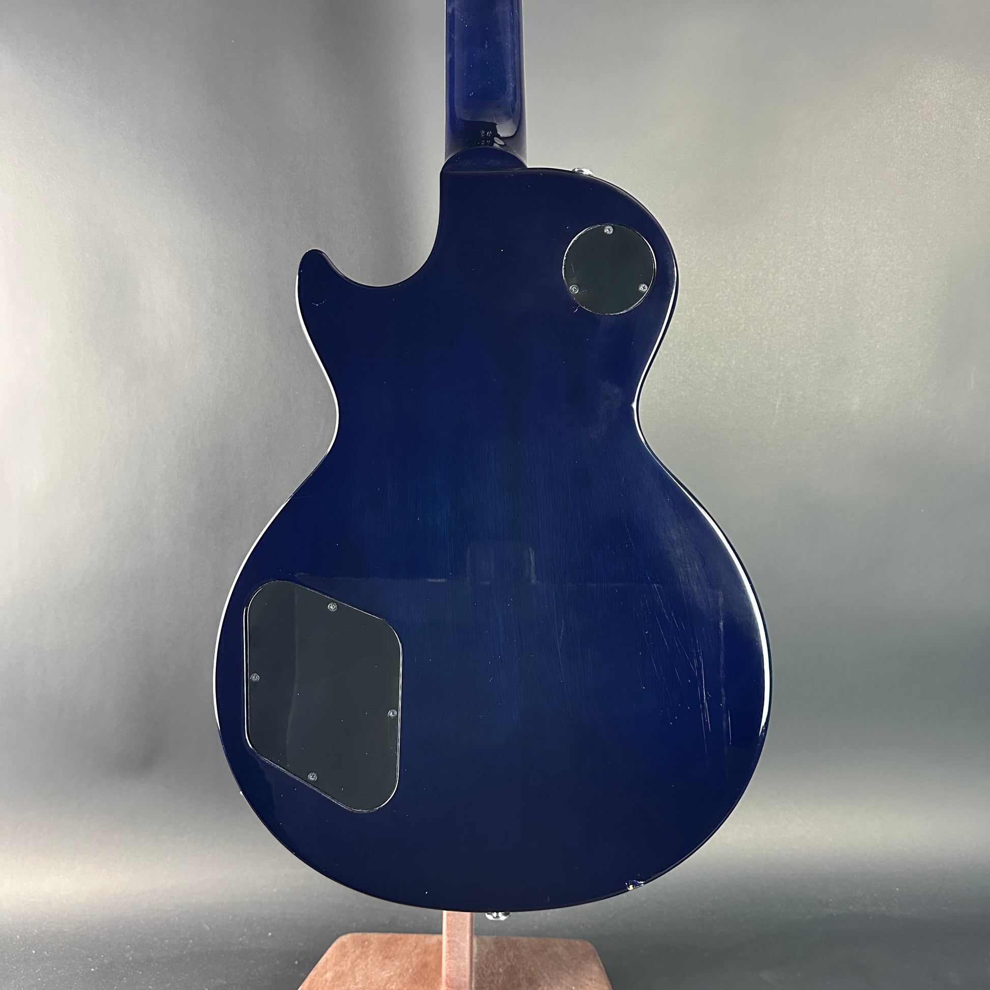 Blue electric guitar body on a stand against a gray background