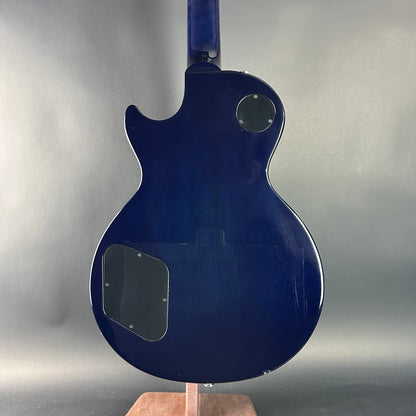 Blue electric guitar body on a stand against a gray background
