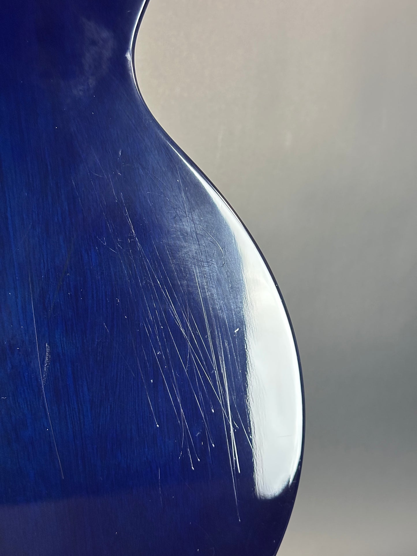 Close-up of a blue spoon with visible scratches on a gray background