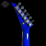 Close-up of the headstock of a blue electric guitar against a black background, showing six tuning pegs and a Tone Shop watermark in the upper left corner.