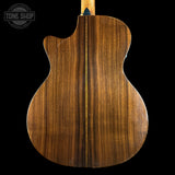 Back view of a wooden acoustic guitar with 'Tone Shop' logo.
