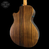 Back view of a wooden acoustic guitar with 'Tone Shop' logo.