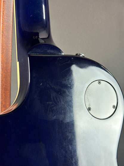 Close-up of a blue guitar with a wooden neck and metal hardware.