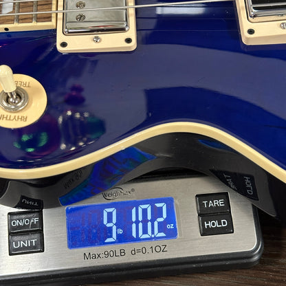 Blue electric guitar on a digital scale displaying weight.