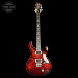 A red double-cutaway electric guitar with a glossy flamed maple body, shown vertically against a solid black background. The guitar features a red body, a dark fretboard, and gold hardware.