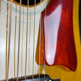 Close-up detail of an acoustic guitar showing the sound hole, strings, bridge, and a glossy reddish-brown body finish.
