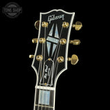 Gibson Les Paul guitar headstock with gold tuning pegs on a black background