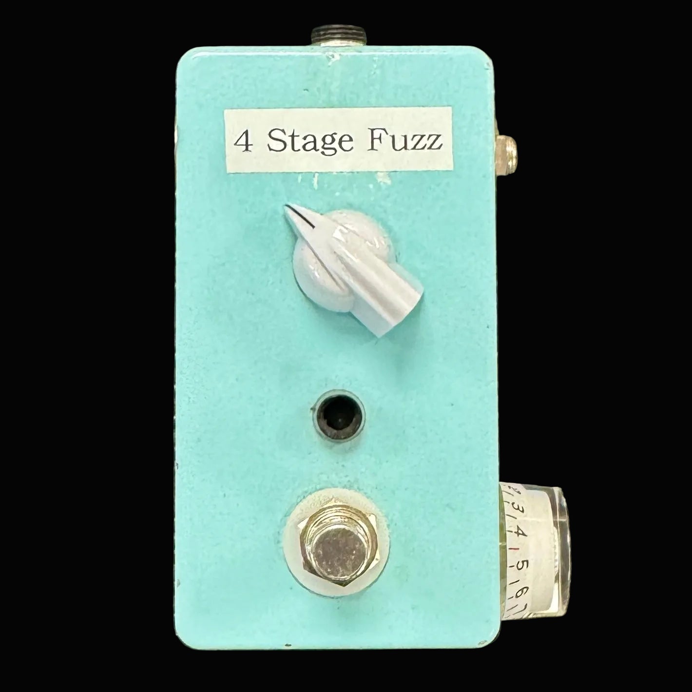 Turquoise guitar effects pedal with '4 Stage Fuzz' label on a textured metal background