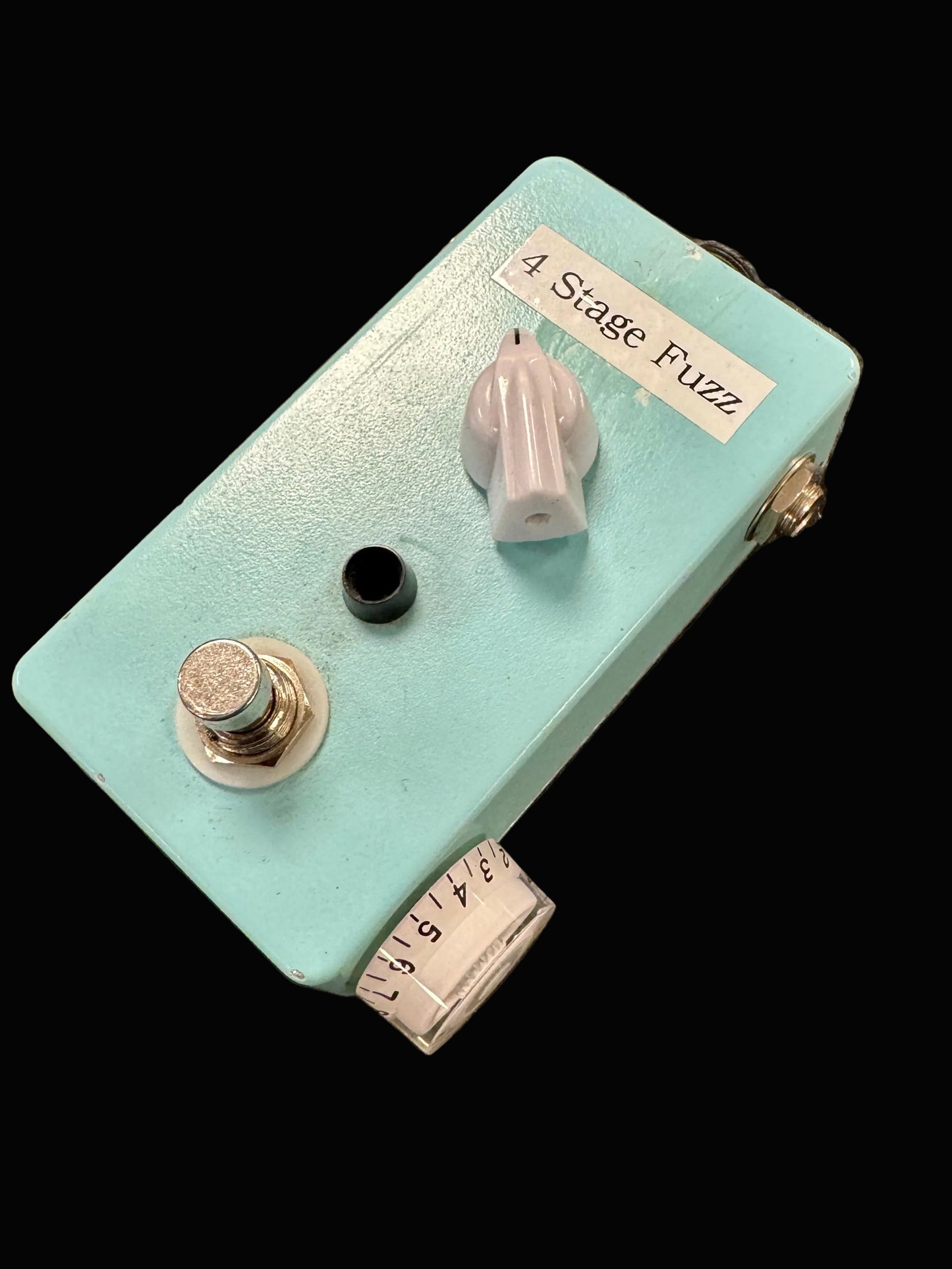 Light blue guitar effects pedal labeled '4 Stage Fuzz' on a textured brown surface
