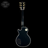 Electric guitar with a black finish on a white background, featuring the Tone Shop logo.
